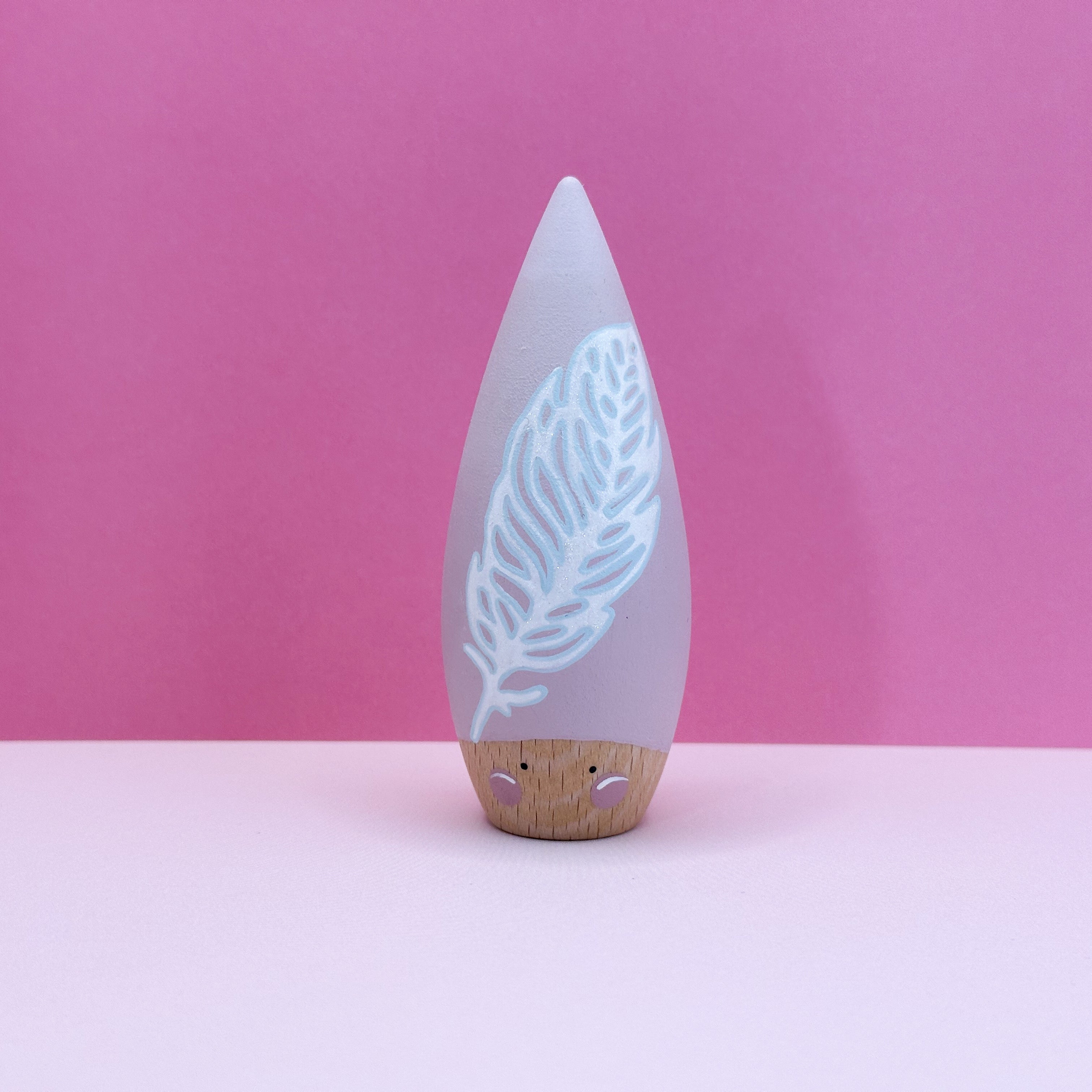 Decorative toy with feather design on a pink background