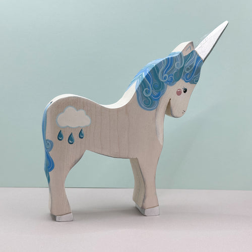 Wooden unicorn figurine with blue hair and rain cloud design on a light green background