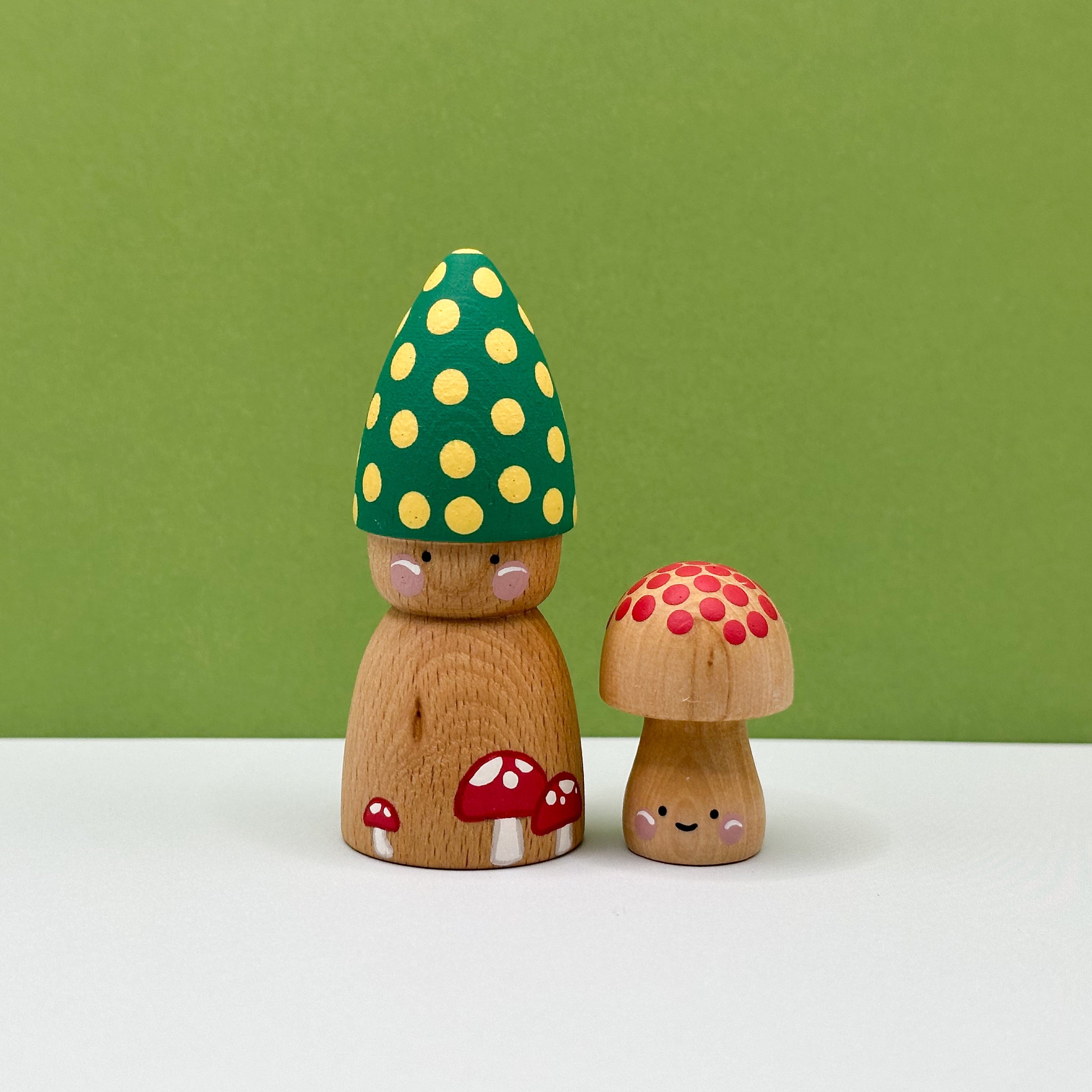 Wooden mushroom figurines with a green polka dot cap on a white surface with a green background