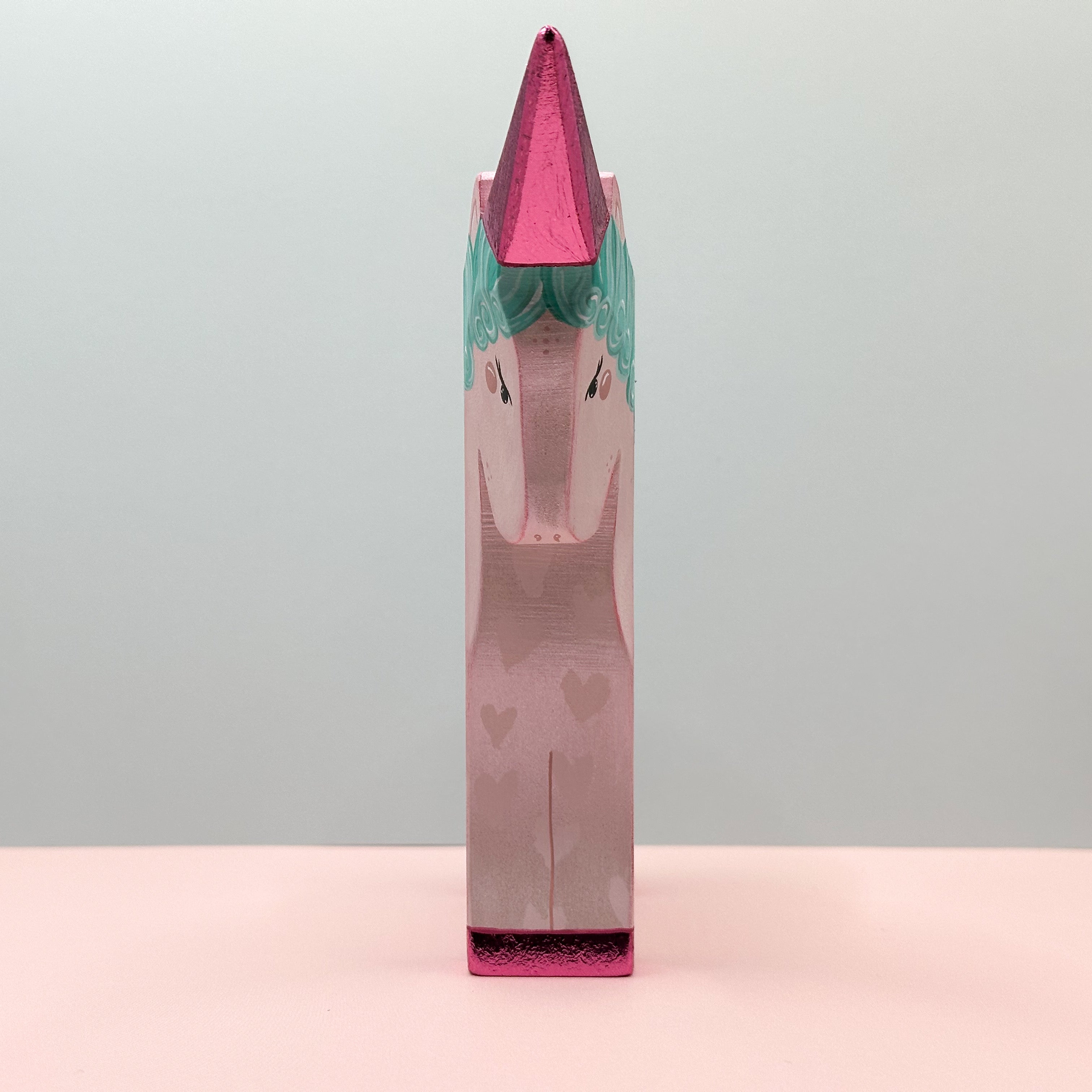 Unicorn-shaped product with pink and green design on a gray background