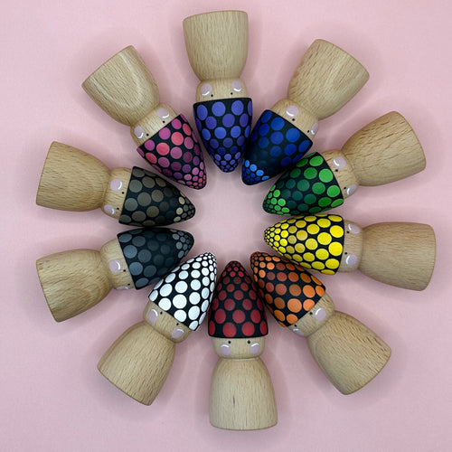 Wooden peg dolls with colorful headbands arranged in a circular pattern on a pink background