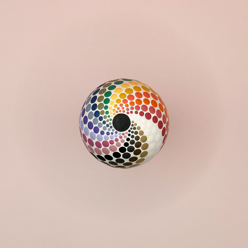 Colorful polka dot ball on a pink background