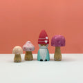 Wooden gnome figurine with mushroom-shaped hats on a white surface against an orange background