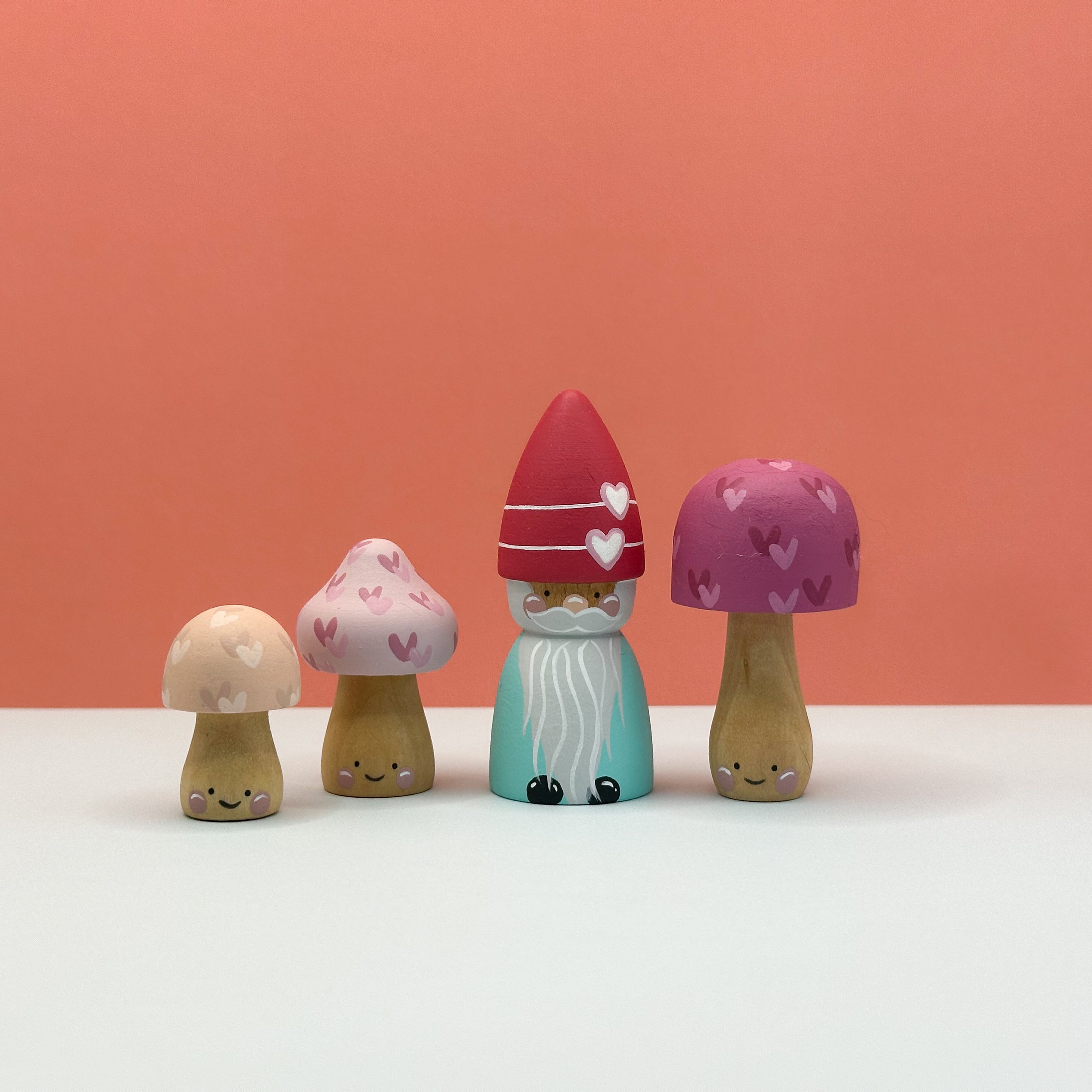 Wooden gnome figurine with mushroom-shaped hats on a white surface against an orange background