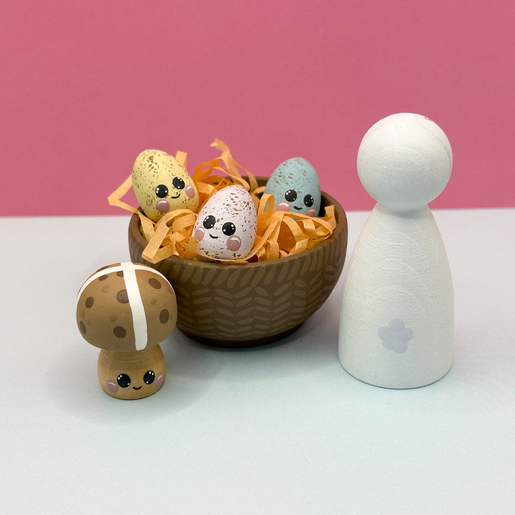 Small decorative items including a bowl with Easter eggs and a mushroom-shaped figure on a pink background.