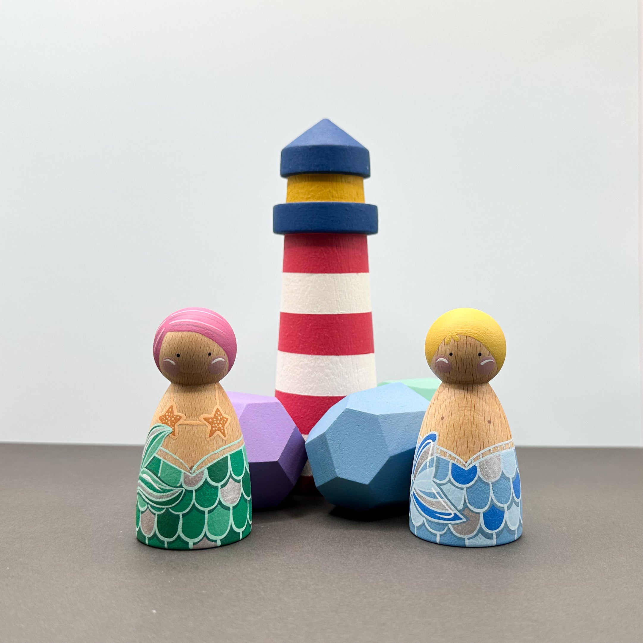 mermaid themed peg doll toys with wooden rocks and a lighthouse. 