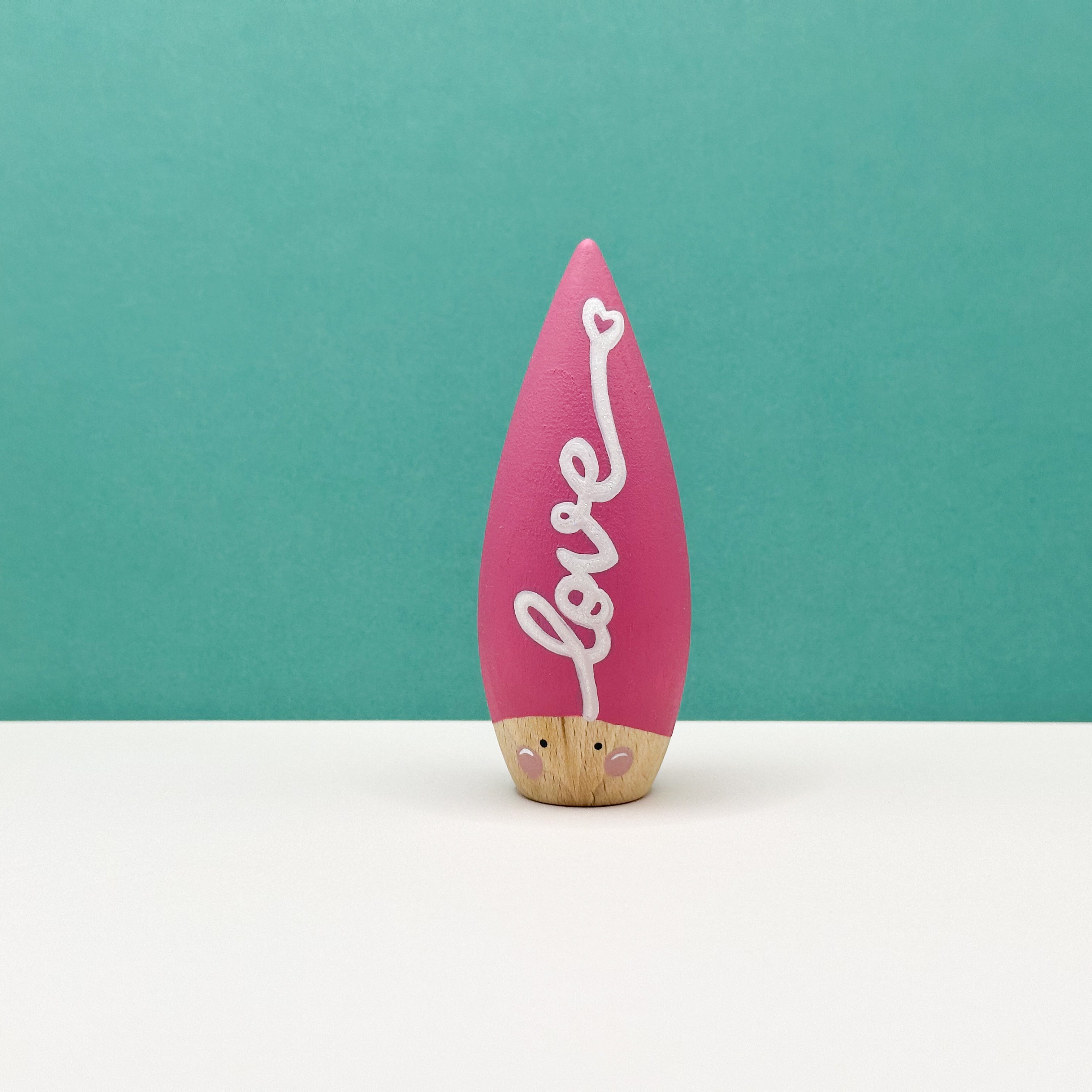 Pink decorative item with 'love' text on a teal background