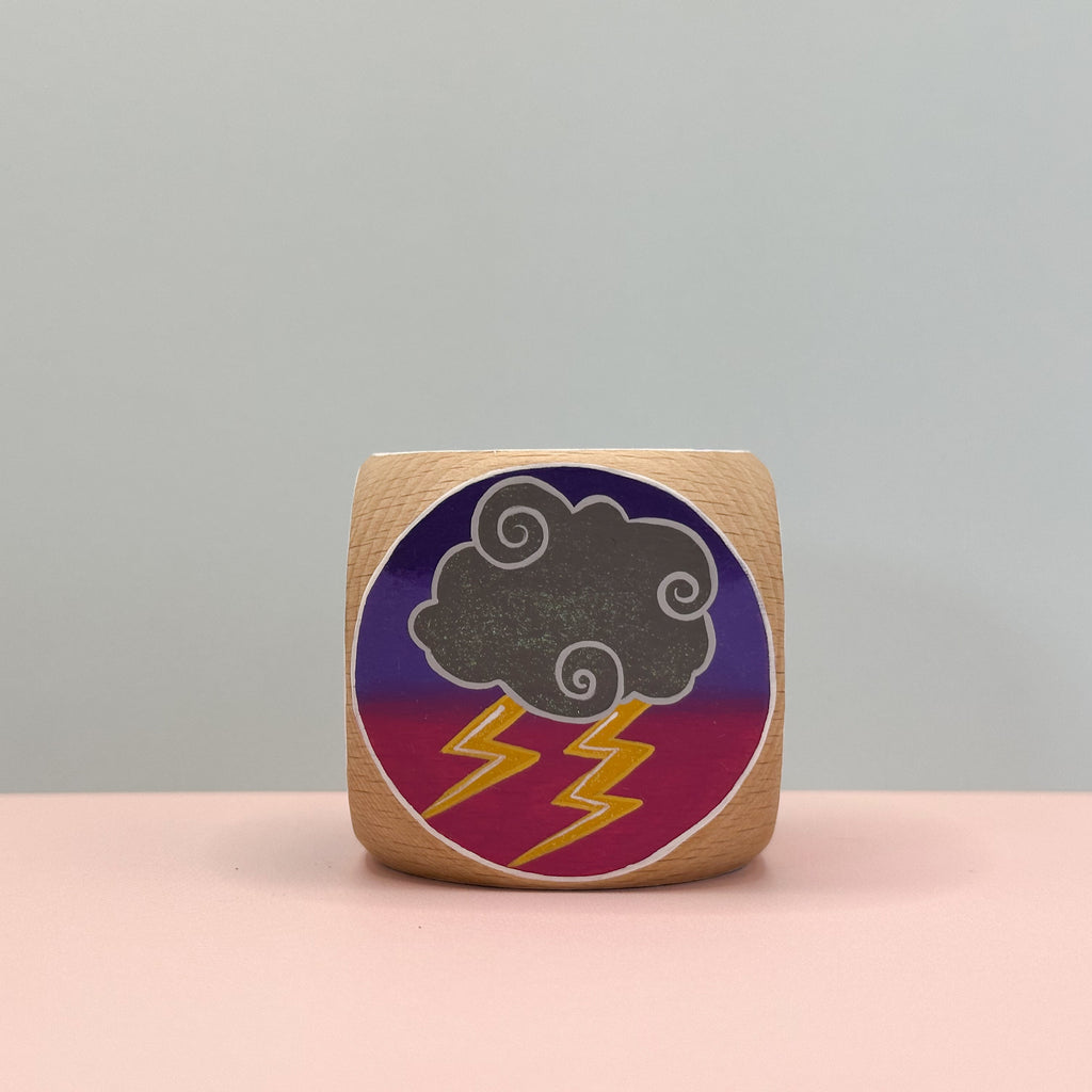 Wooden block with a cloud and lightning design on a gray background