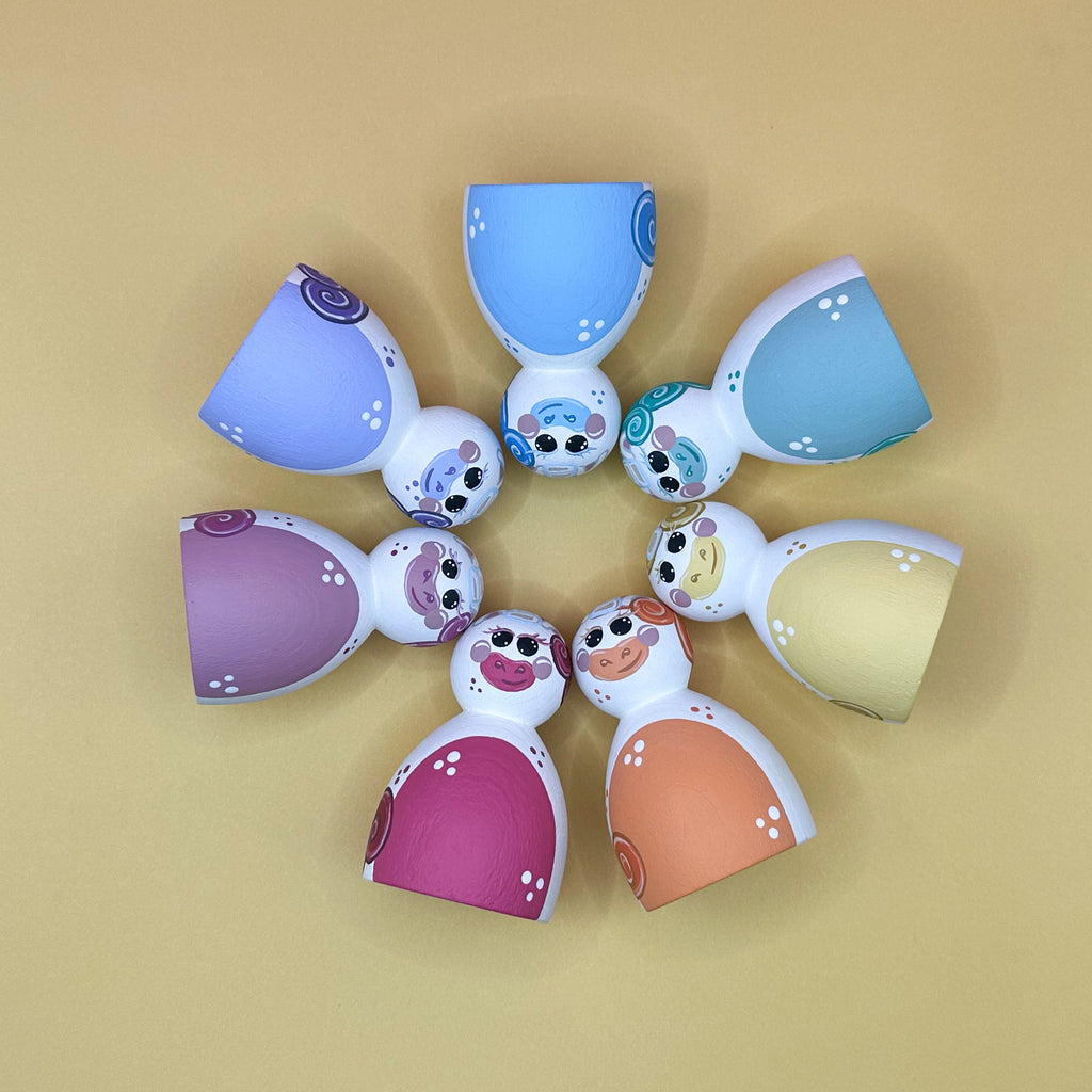 Colorful unicorn-shaped toys arranged in a circle on a beige background
