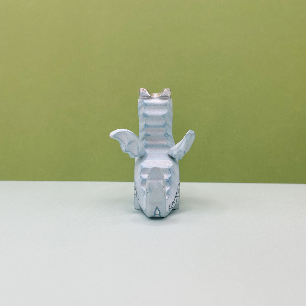 A small wooden light blue dragon on a green background