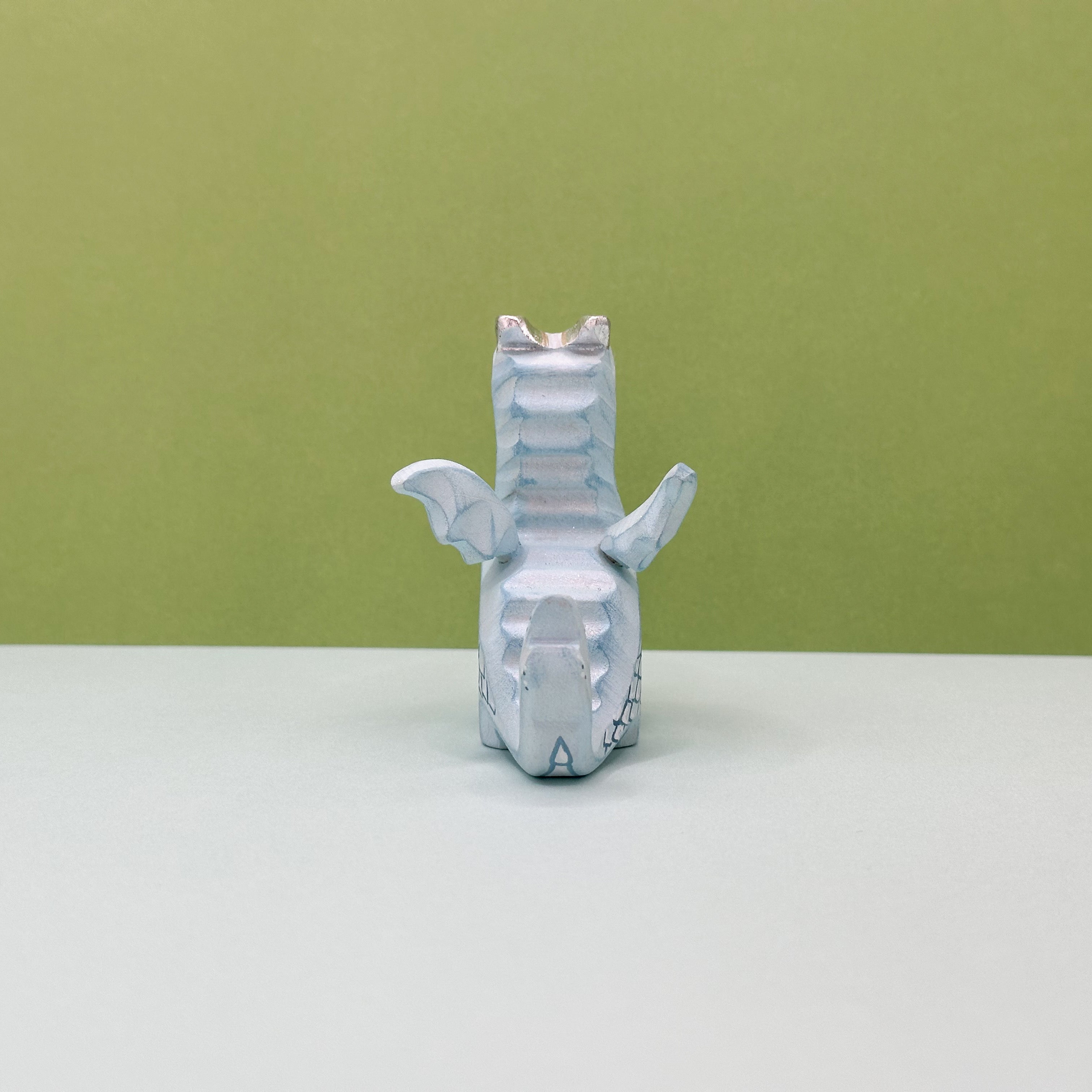 A small wooden light blue dragon on a green background
