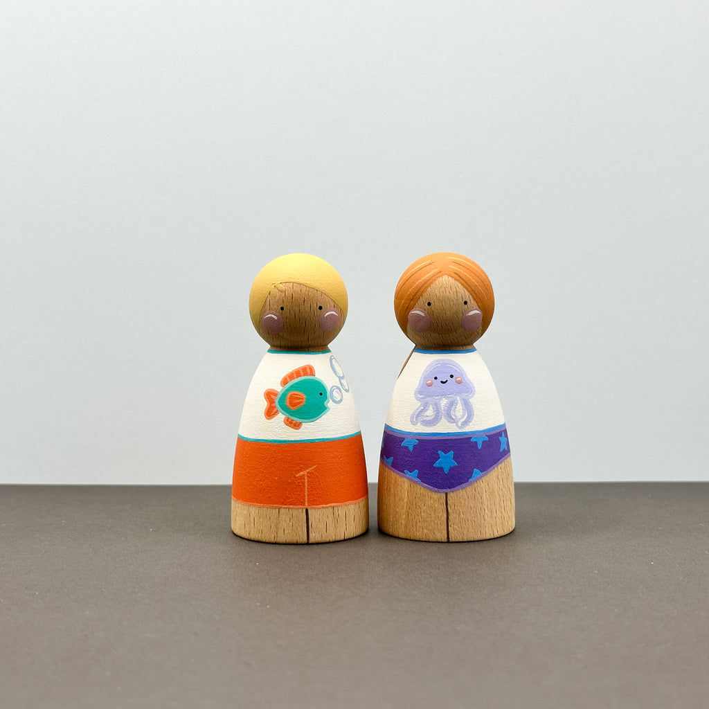 Two wooden peg dolls wearing sun safe swimwear