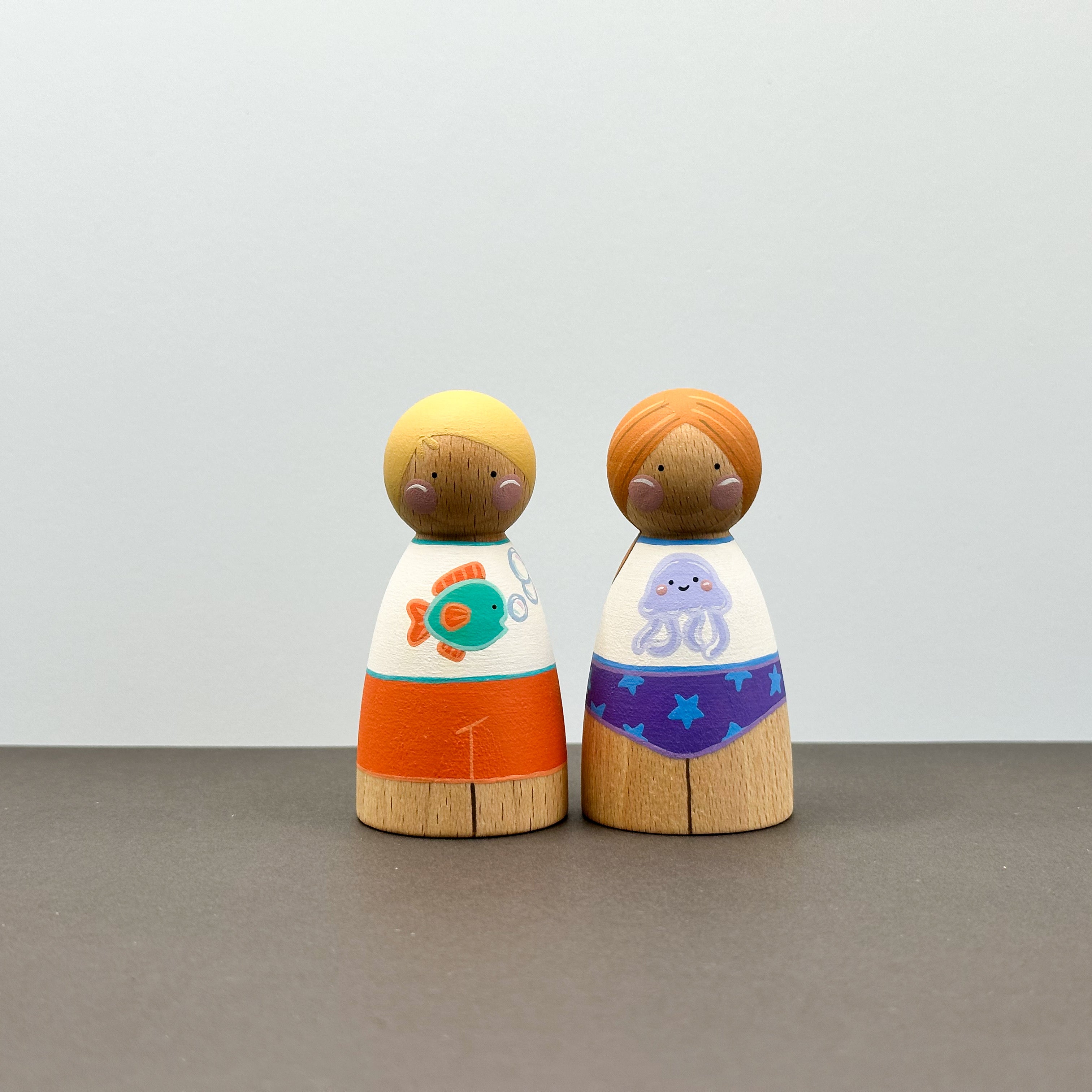 Two wooden peg dolls wearing sun safe swimwear