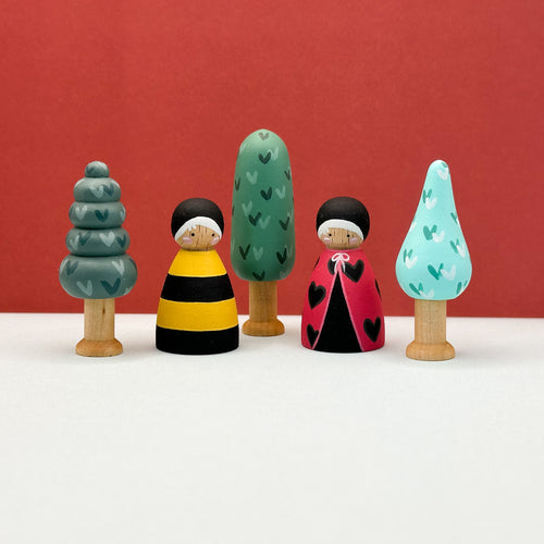 Set of colorful wooden figurines with trees against a red background