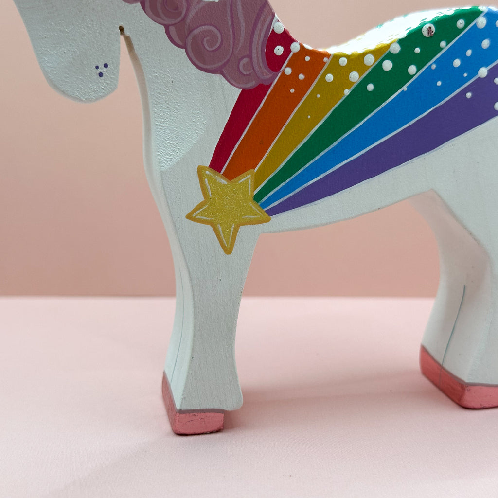 Colorful unicorn figurine with a rainbow and star on a pink background