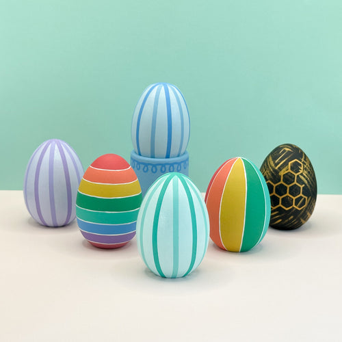 Colorful striped eggs on a light surface with a light green background