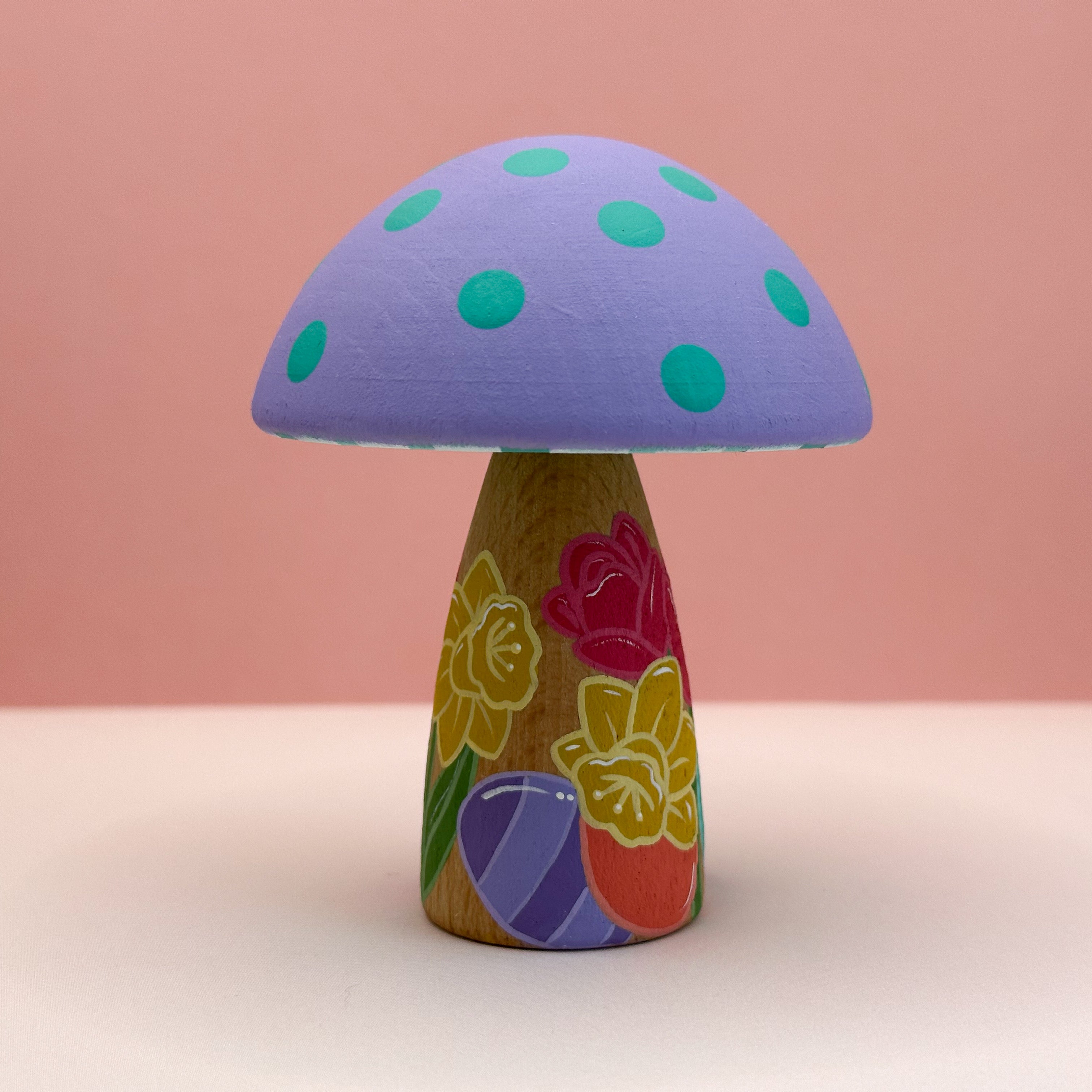 Colorful mushroom-shaped object with a purple cap and wooden base featuring floral designs on a pink background.
