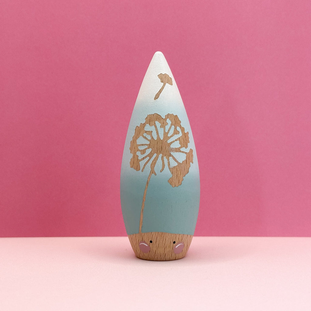 Wooden dandelion figure with a gradient mint green to white design on a pink background