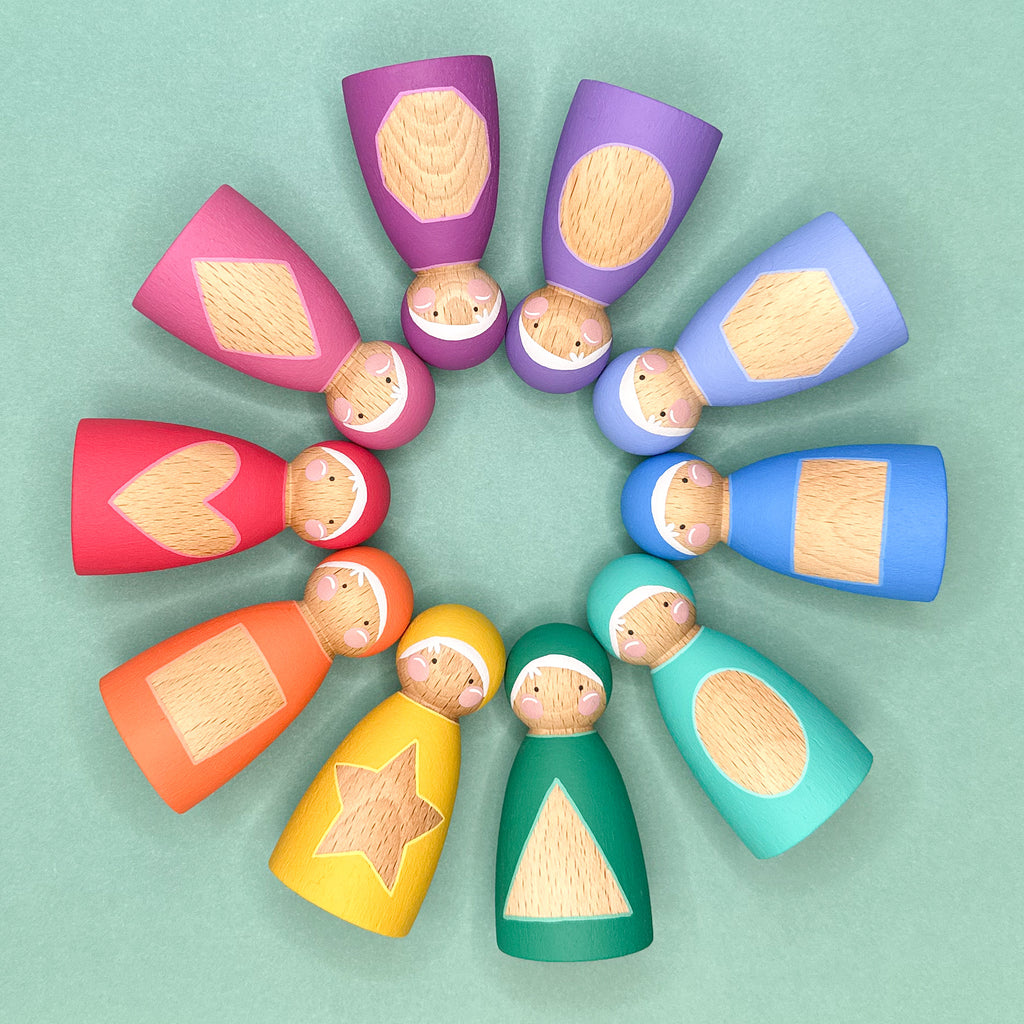 Colorful wooden dolls arranged in a circular pattern on a light green background. The dolls have shape patterns on their tummies. 