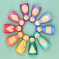 Colorful wooden dolls arranged in a circular pattern on a light green background. The dolls have shape patterns on their tummies. 