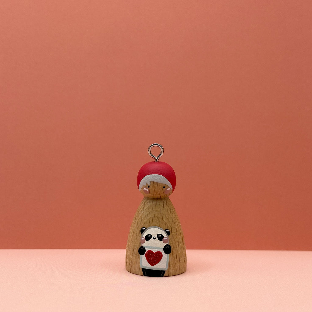 Small peg doll keyring with a panda holding a heart sign painted on its body with a peach background