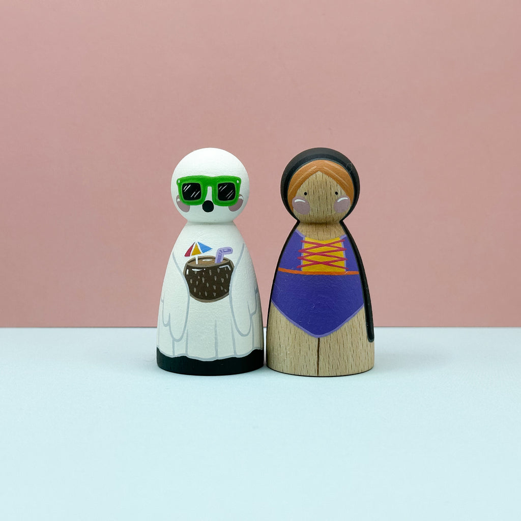 Two wooden peg dolls with colorful outfits against a pink background