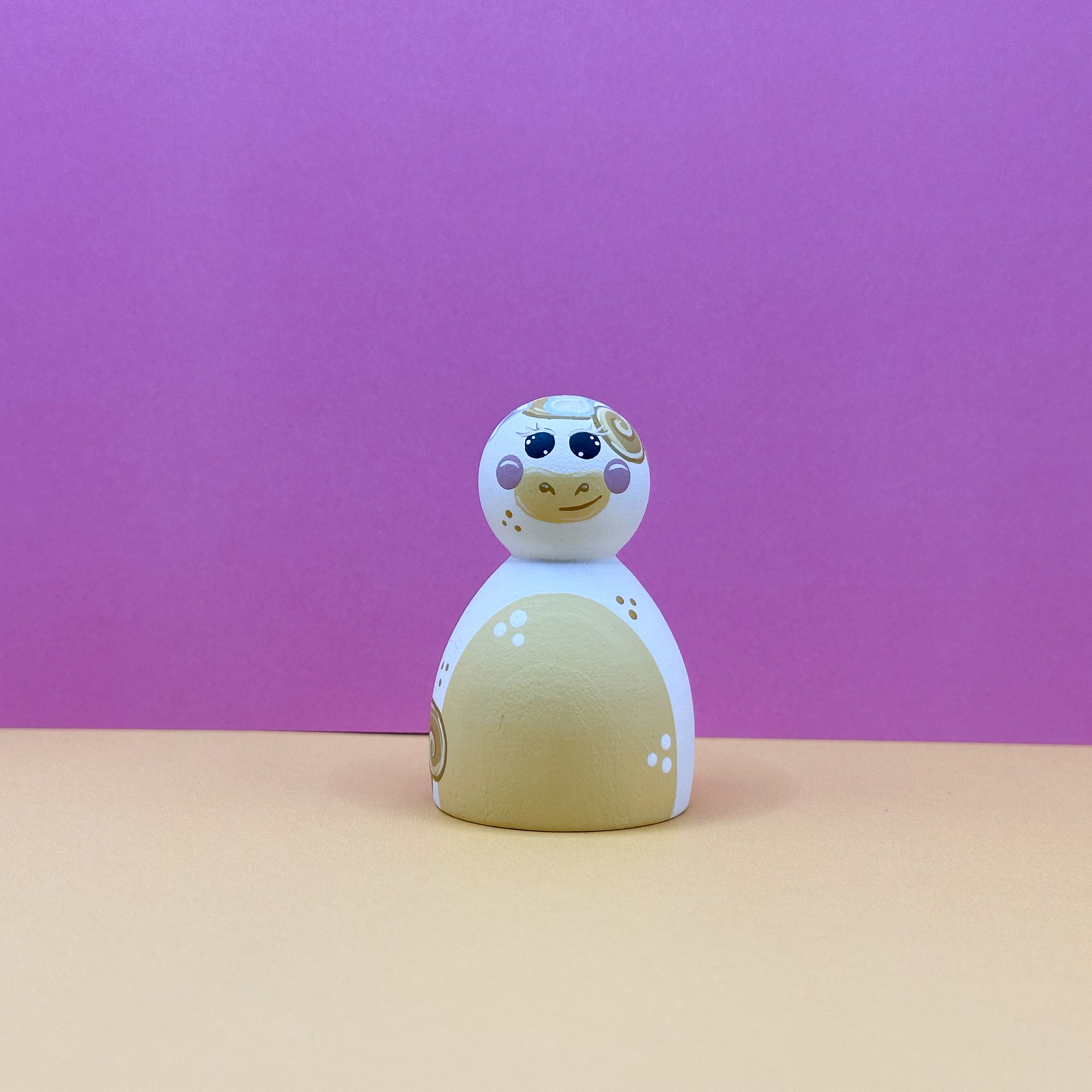 Toy figure with a white face and beige body on a pink background