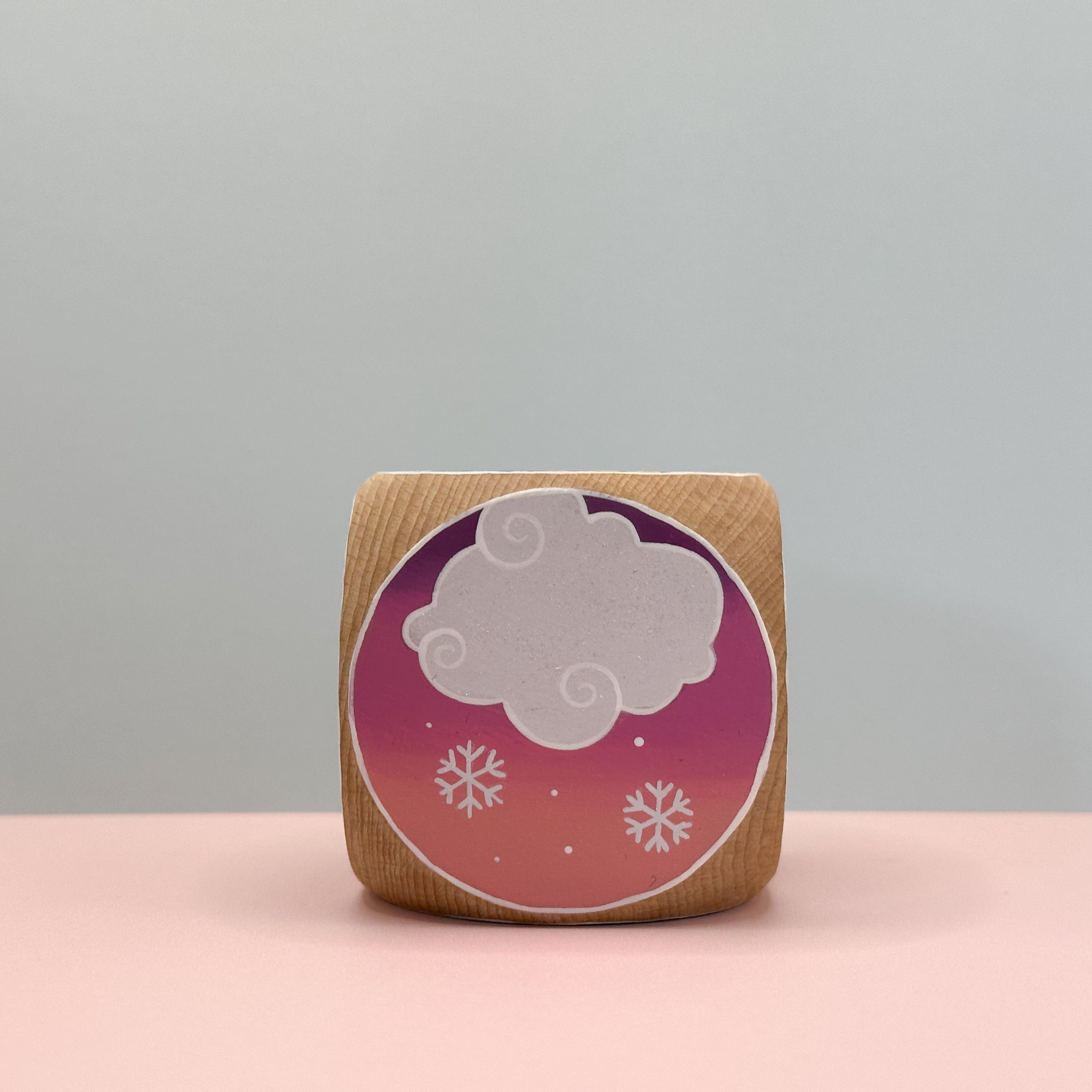 Wooden block with a cloud and snowflake design on a gradient background