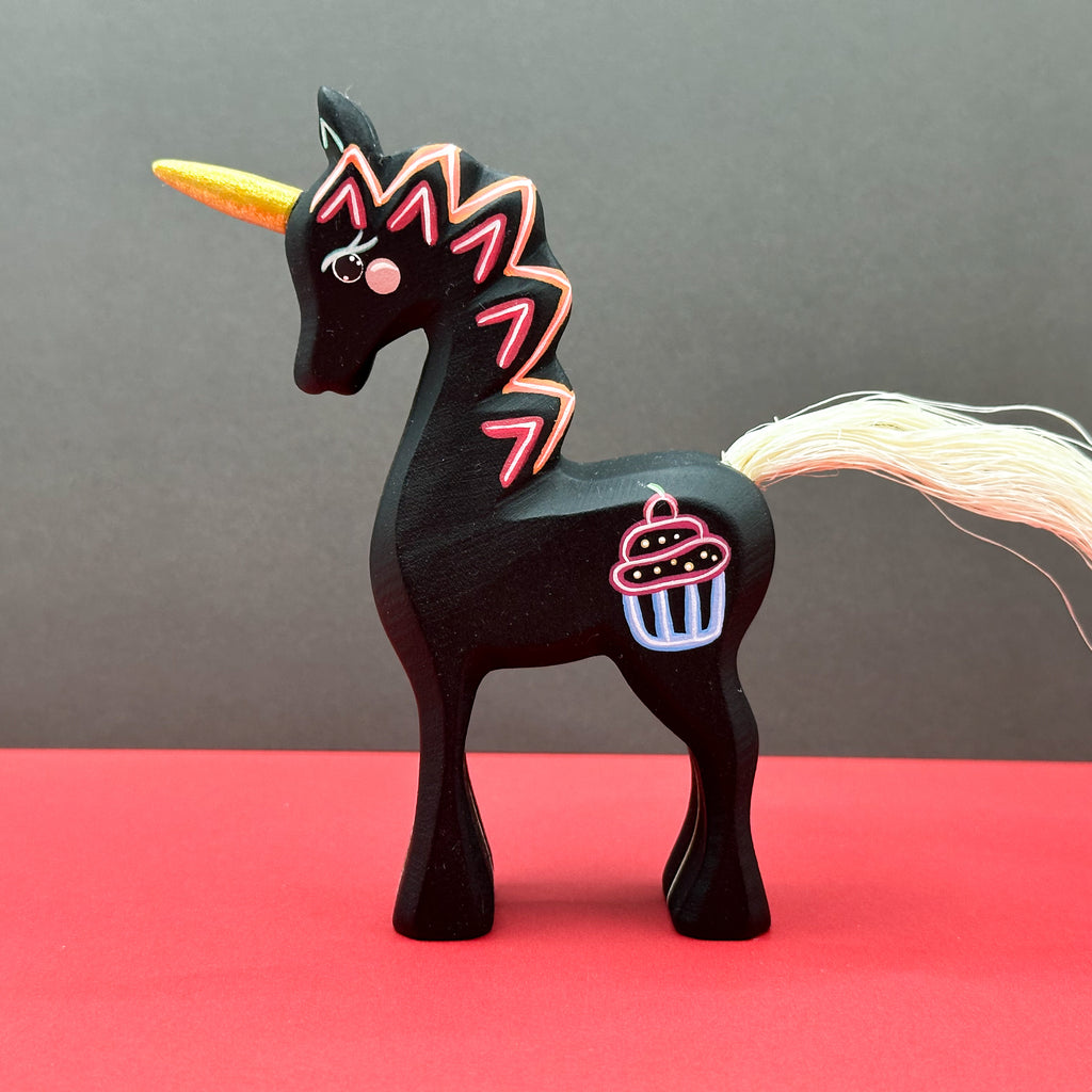 Black unicorn figurine with colorful design on a red and gray background