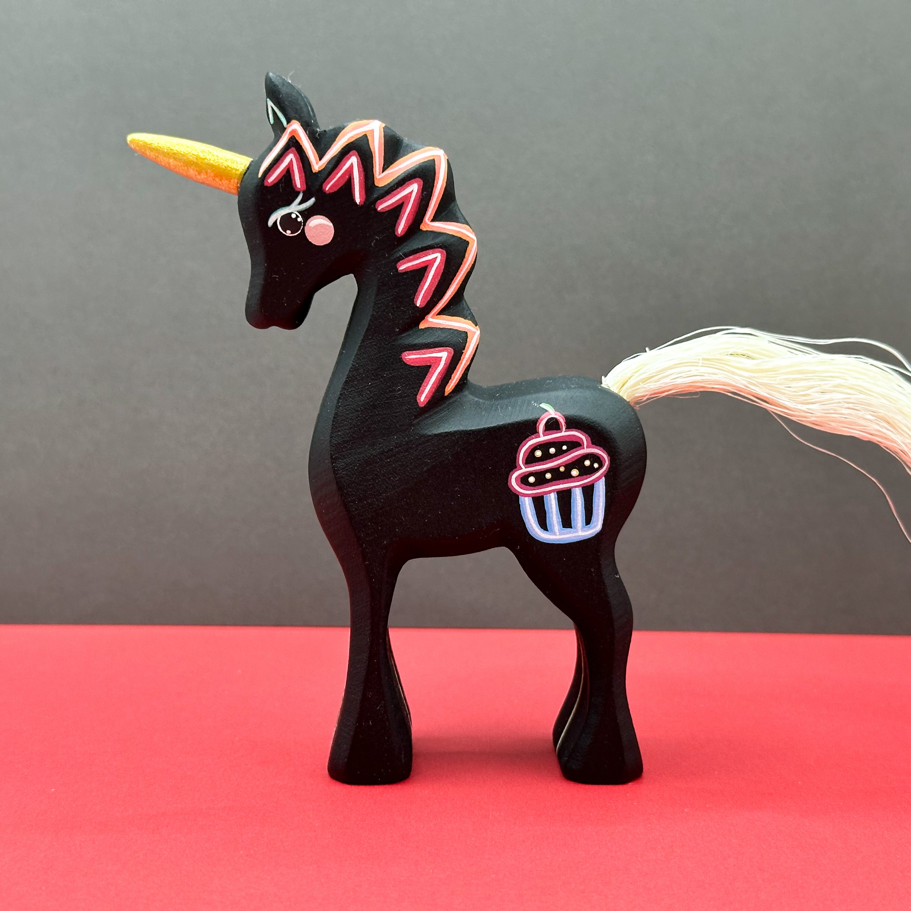Black unicorn figurine with colorful design on a red and gray background