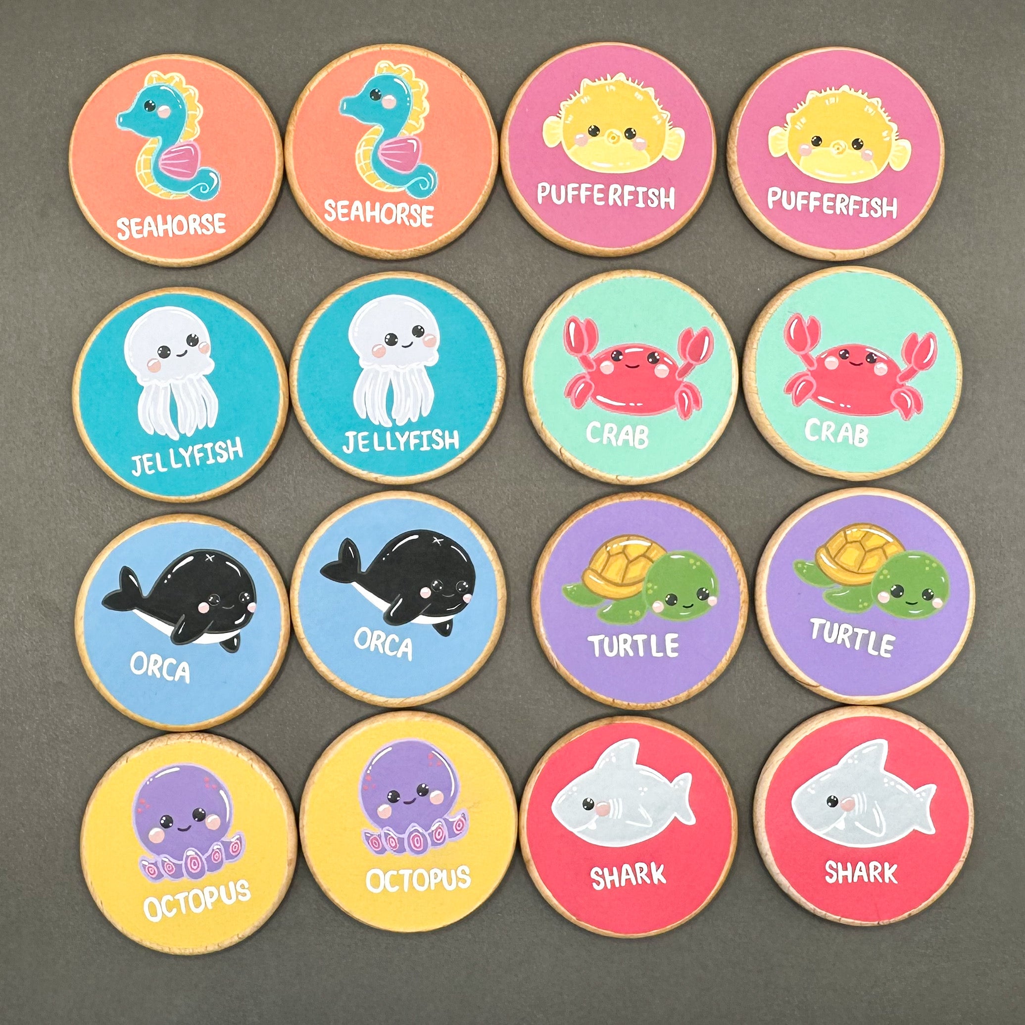 Colourful wooden discs with sea creatures painted on them. On a black surface