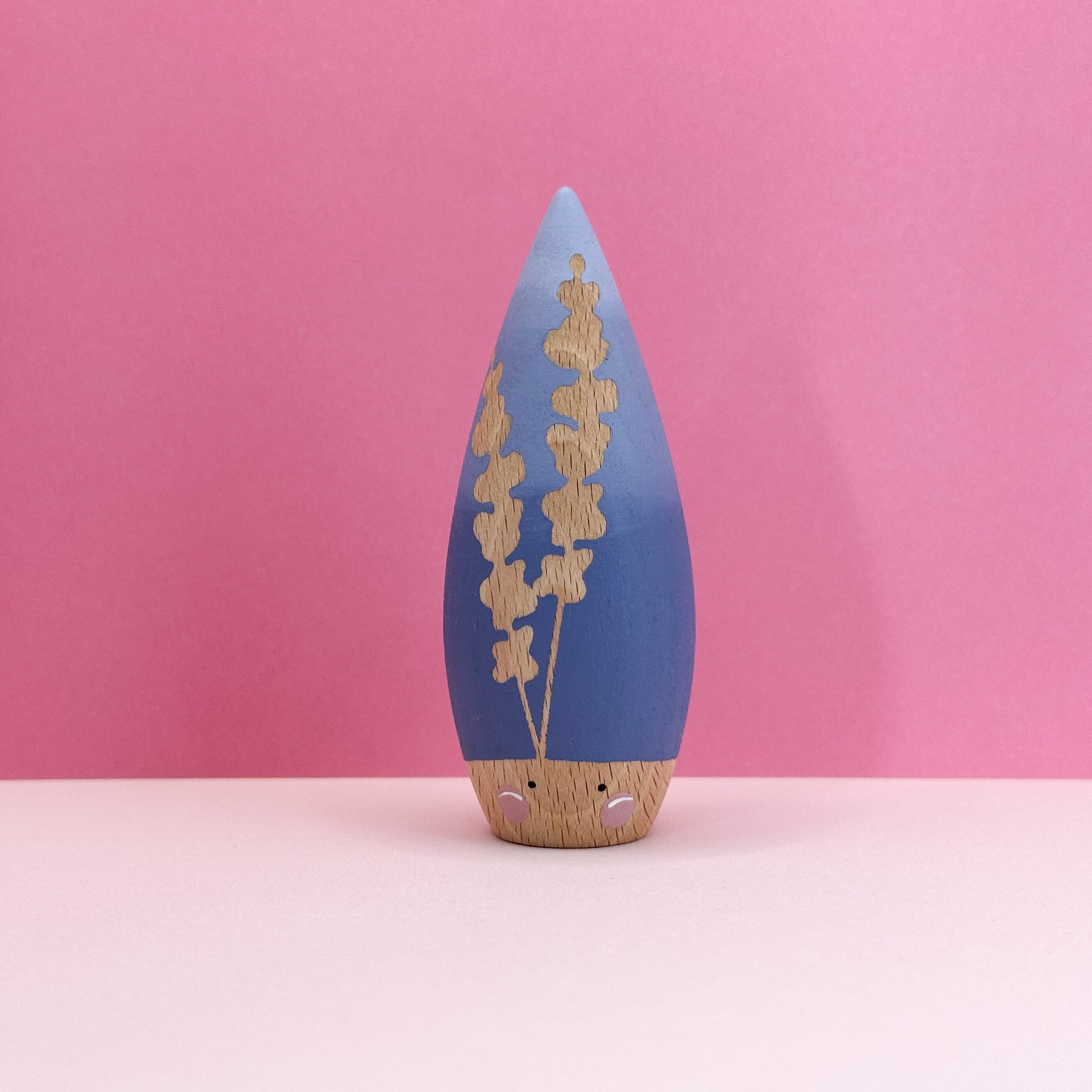 Decorative toy with blue top and wooden bottom on a pink background