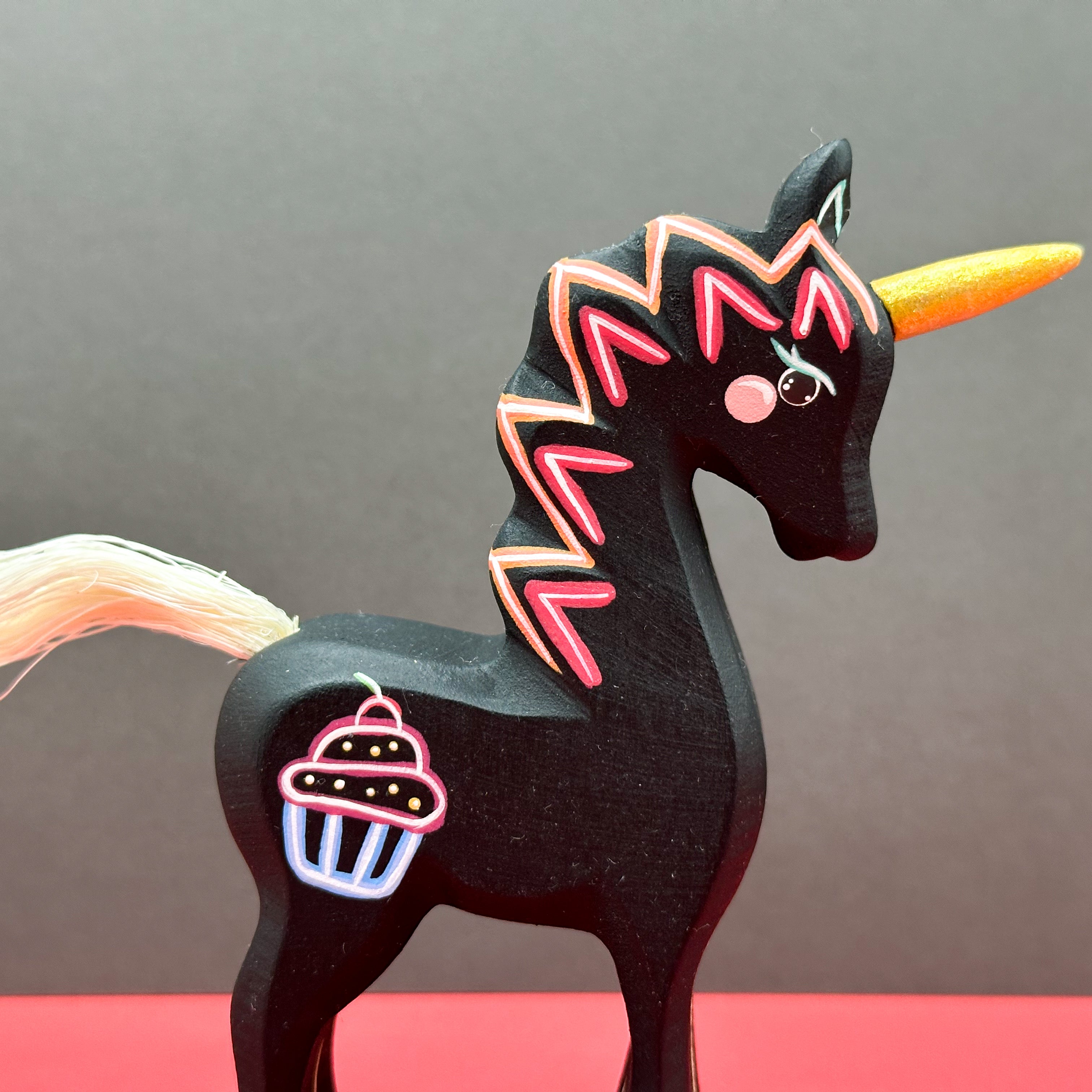 Black unicorn figurine with colorful design on a gray background