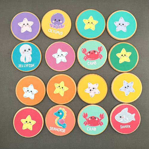 Colourful wooden discs with sea creatures painted on them. On a black surface