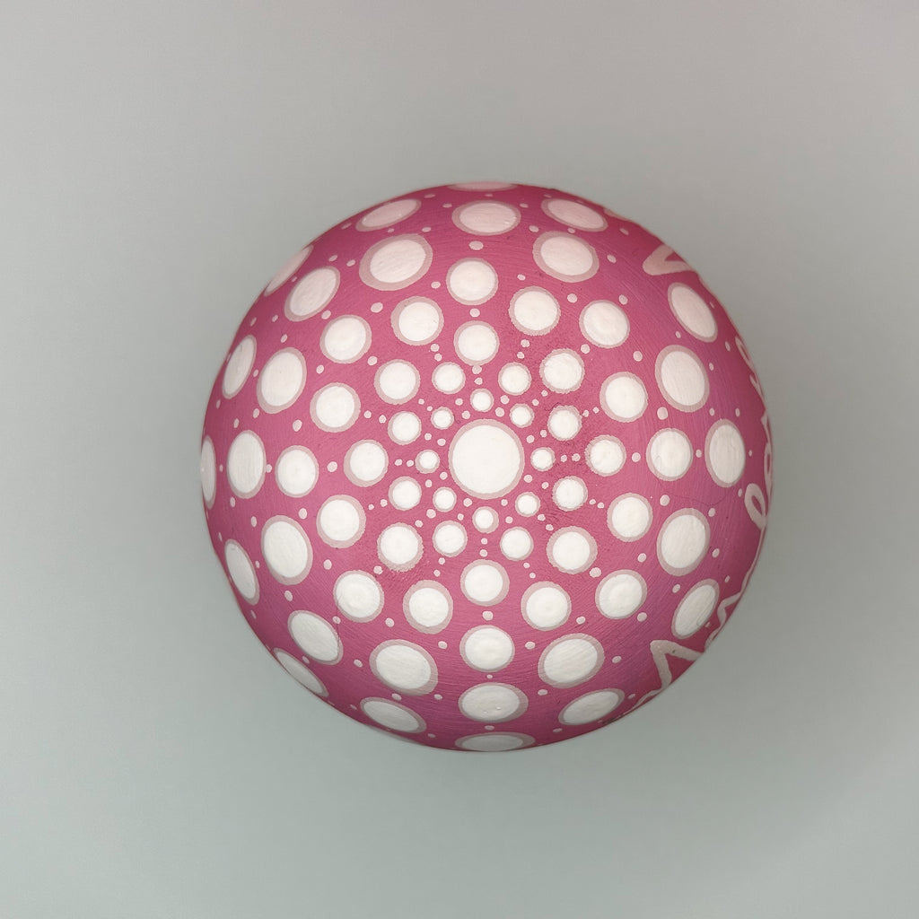 Pink ball with white circular pattern on a gray background