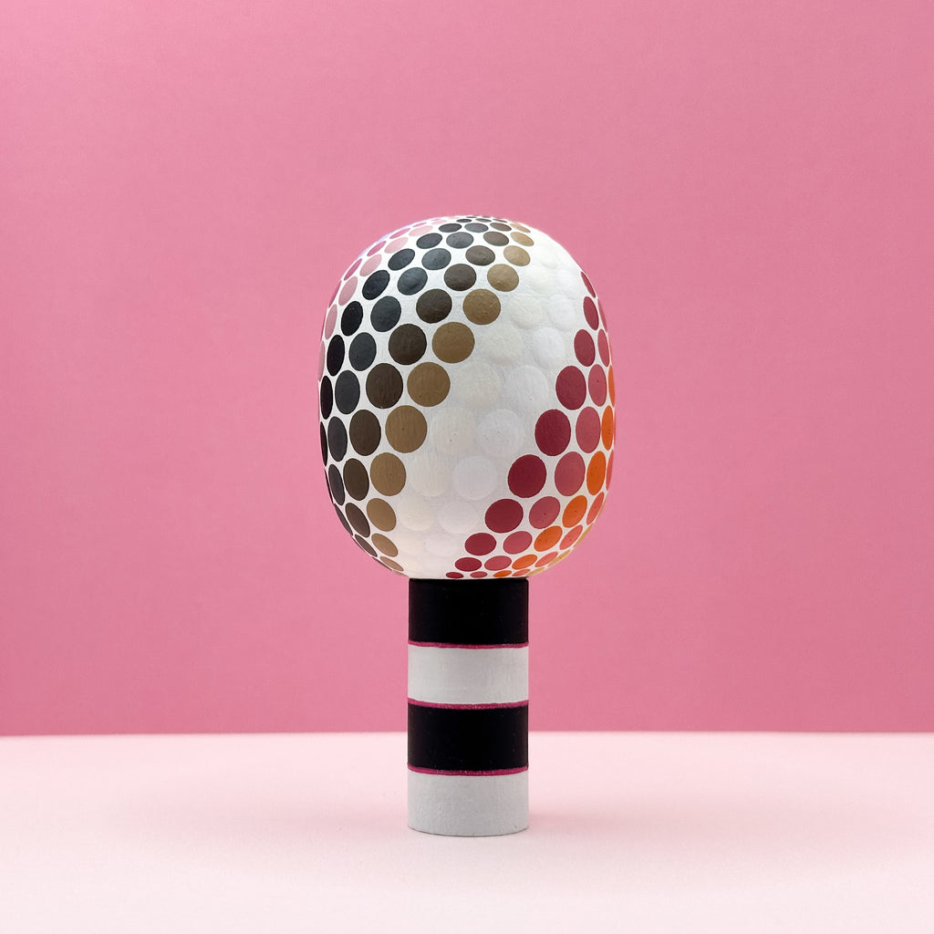 Decorative object with a polka dot design on a pink background