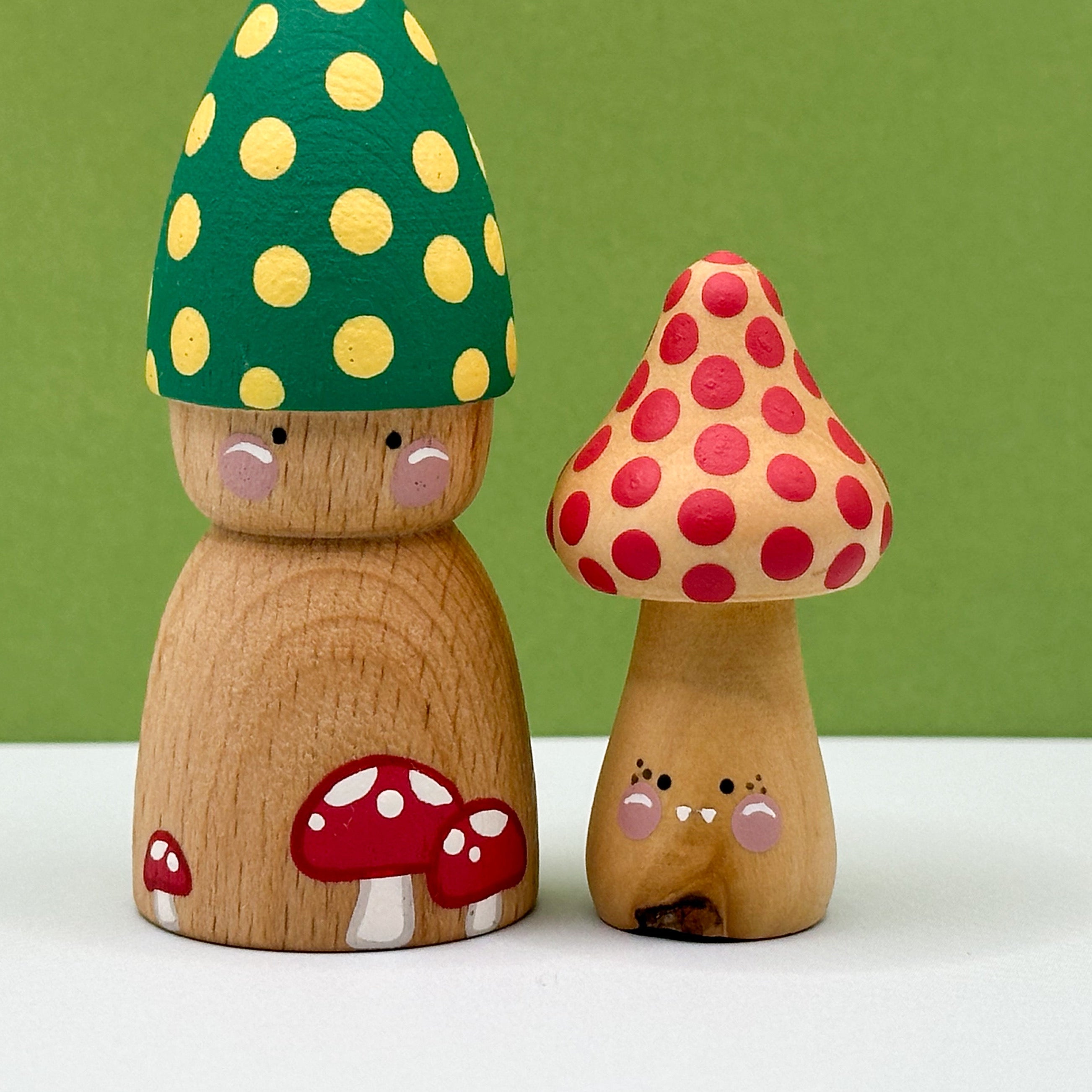 Wooden mushroom figurines with colorful caps on a white surface and green background