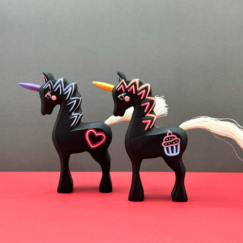 Two black unicorn figurines with colorful designs on a red and gray background
