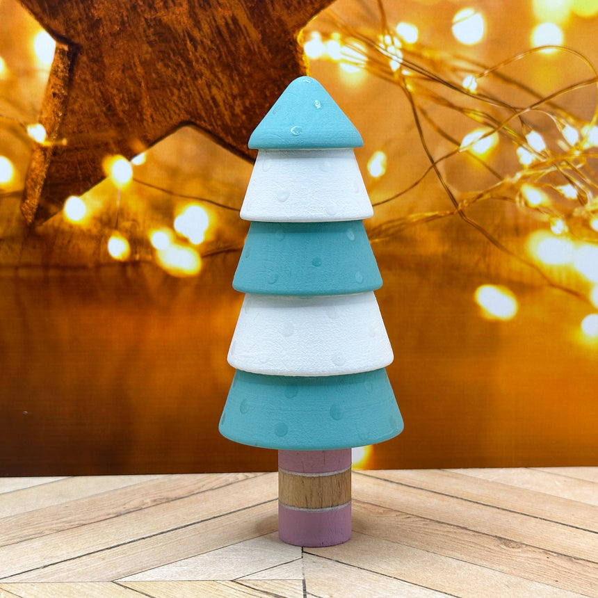 Colorful Christmas tree-shaped toy on a wooden surface with blurred lights in the background