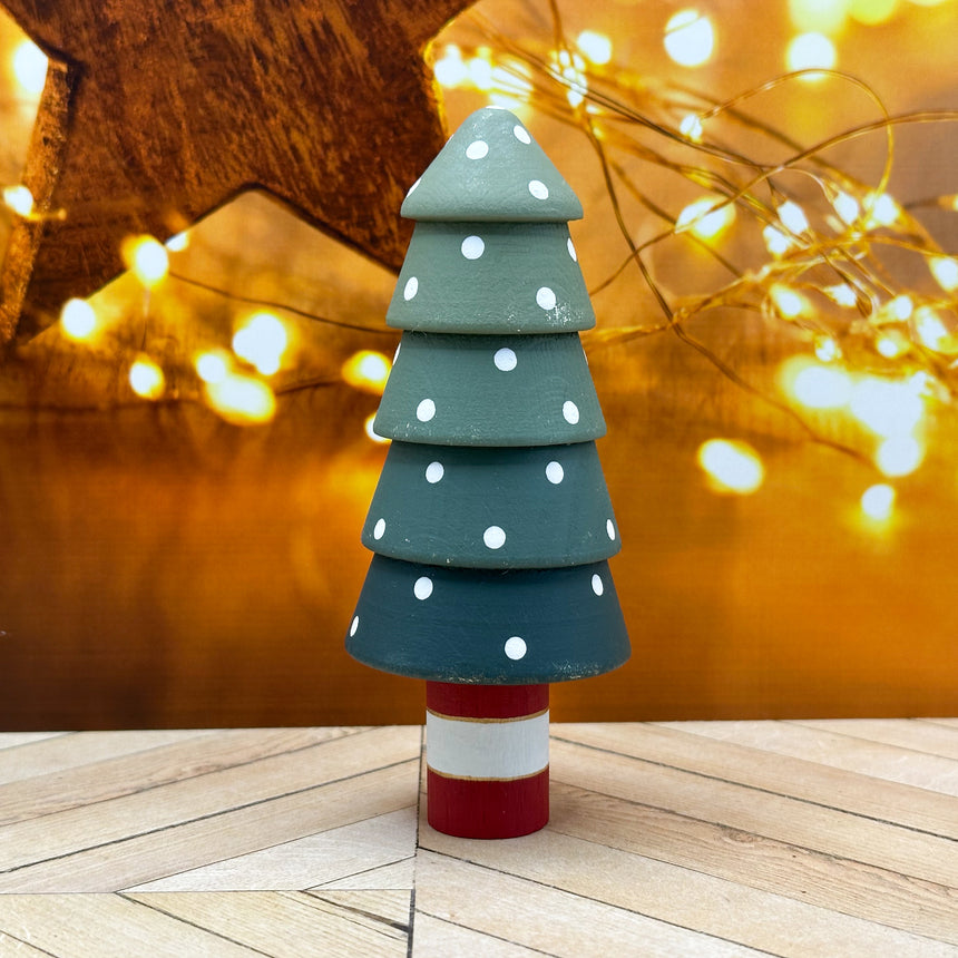 Decorative Christmas tree with polka dot design on a wooden surface with blurred lights in the background