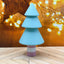Colorful Christmas tree-shaped toy on a wooden surface with blurred lights in the background