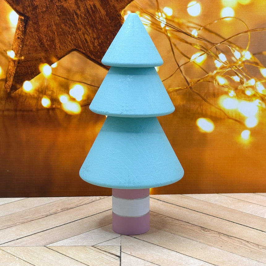 Colorful Christmas tree-shaped toy on a wooden surface with blurred lights in the background