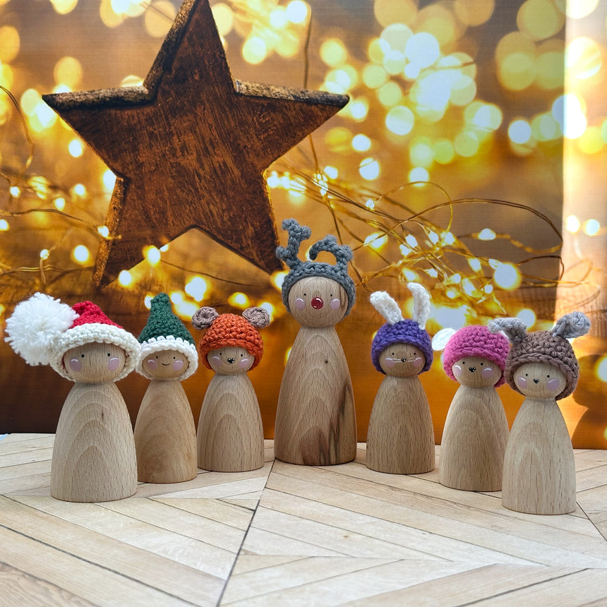 Wooden figurines wearing colorful hats with a star and lights in the background