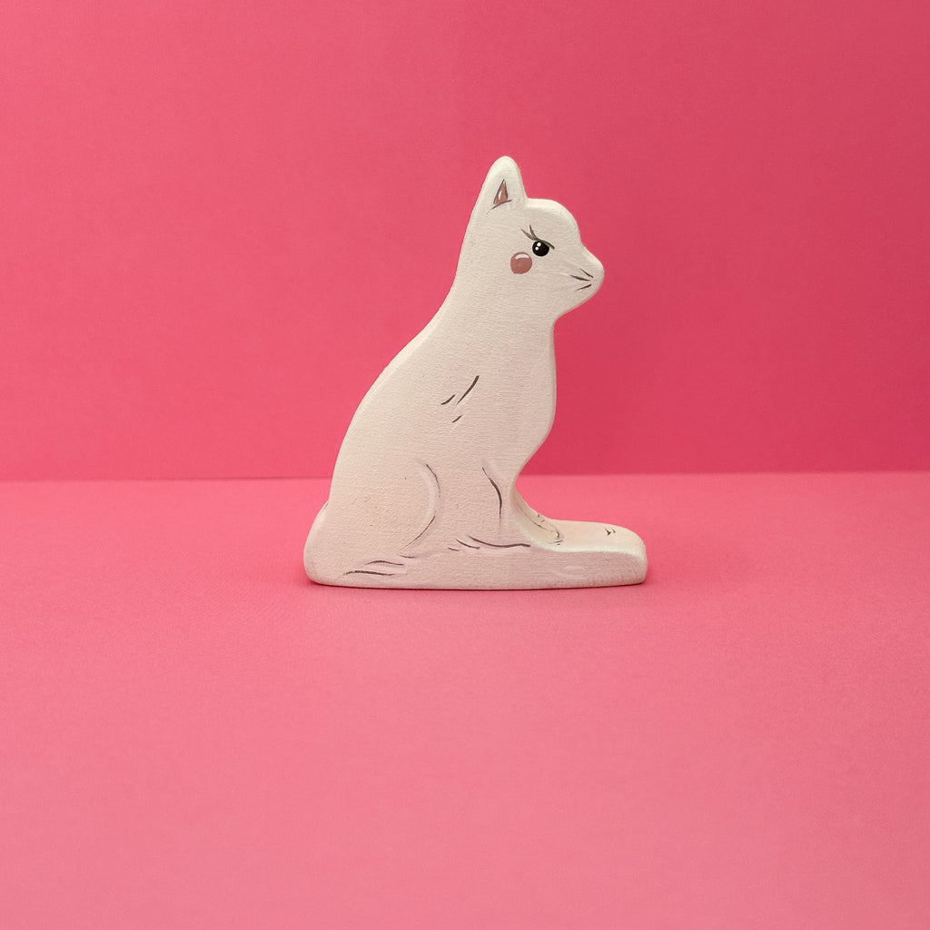 White cat figurine on a pink background