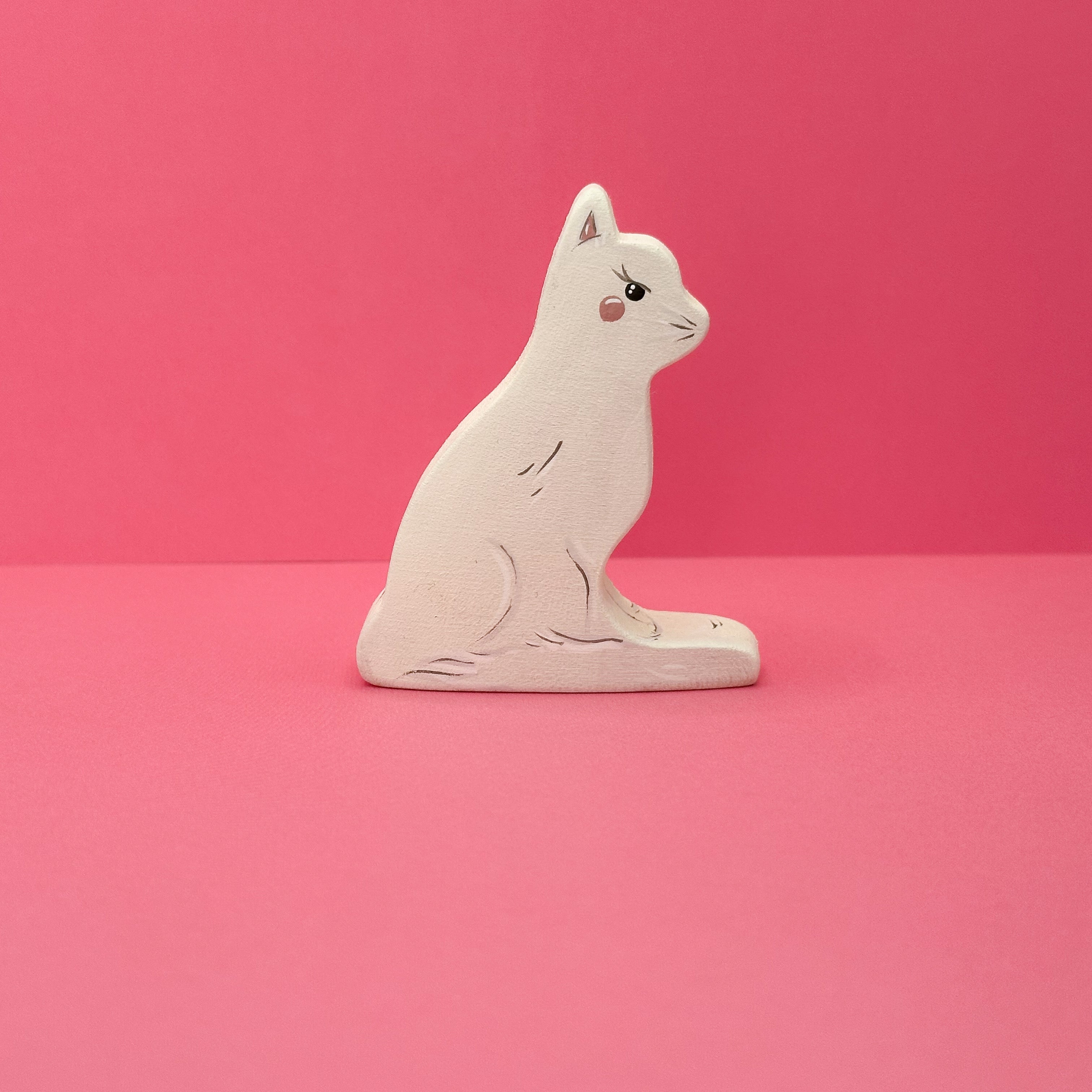 White cat figurine on a pink background