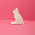 White wooden cat figurine on a pink background