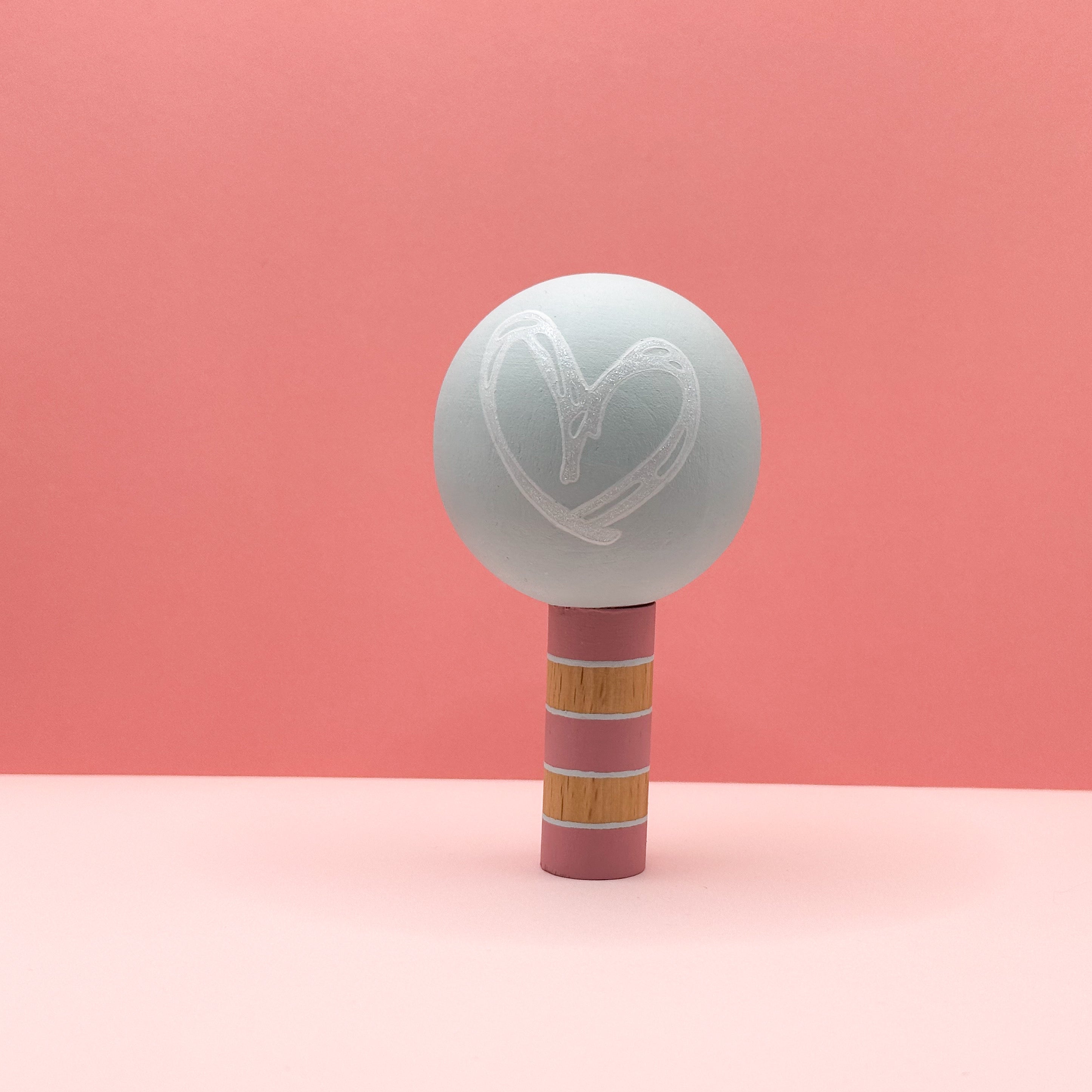 Light green spherical tree with a pink striped trunk on a pink background