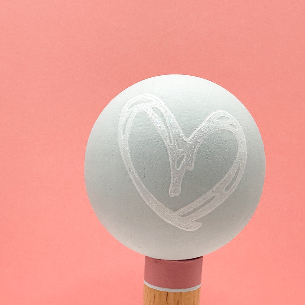 Light green spherical tree with a heart design on a pink background