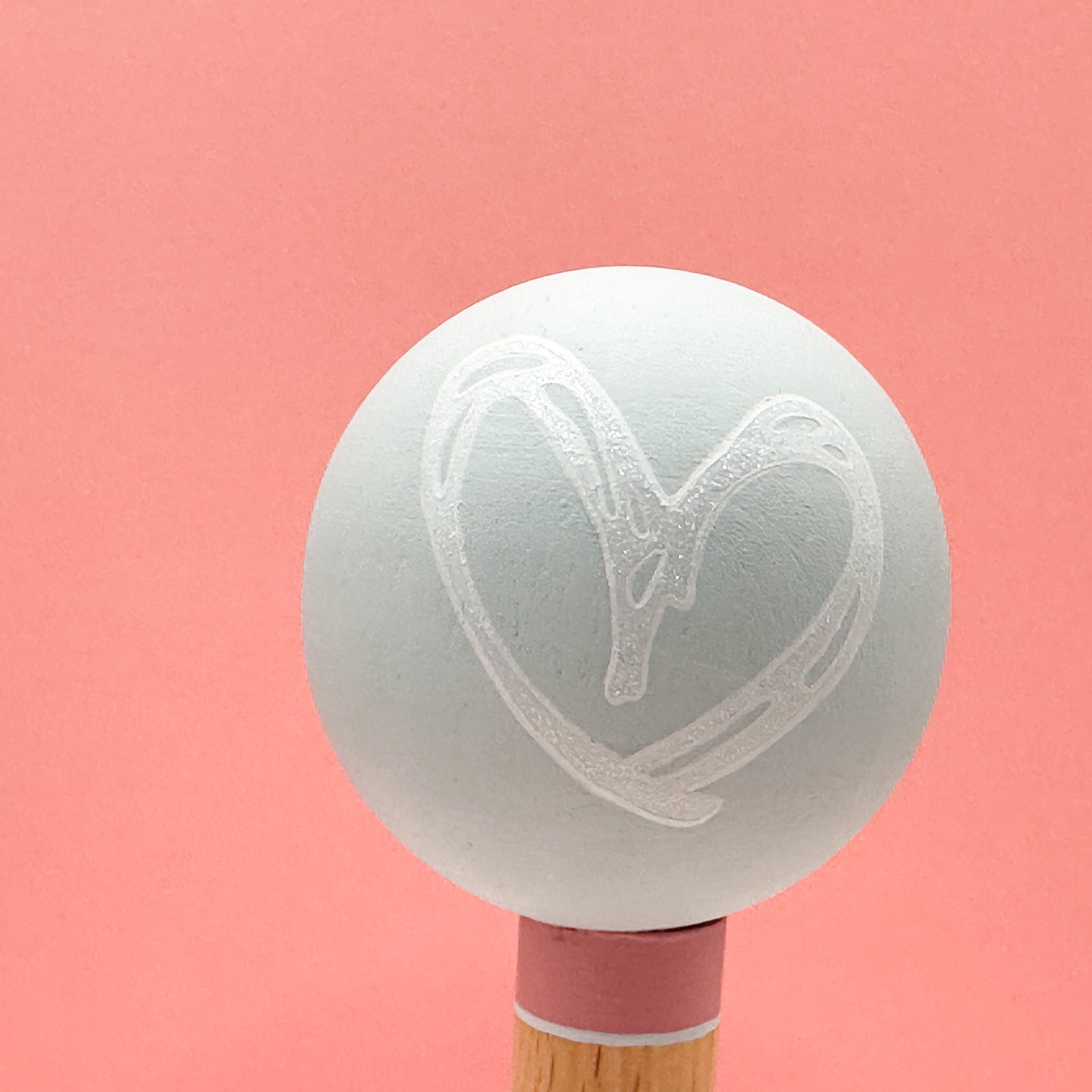 Light green spherical tree with a heart design on a pink background