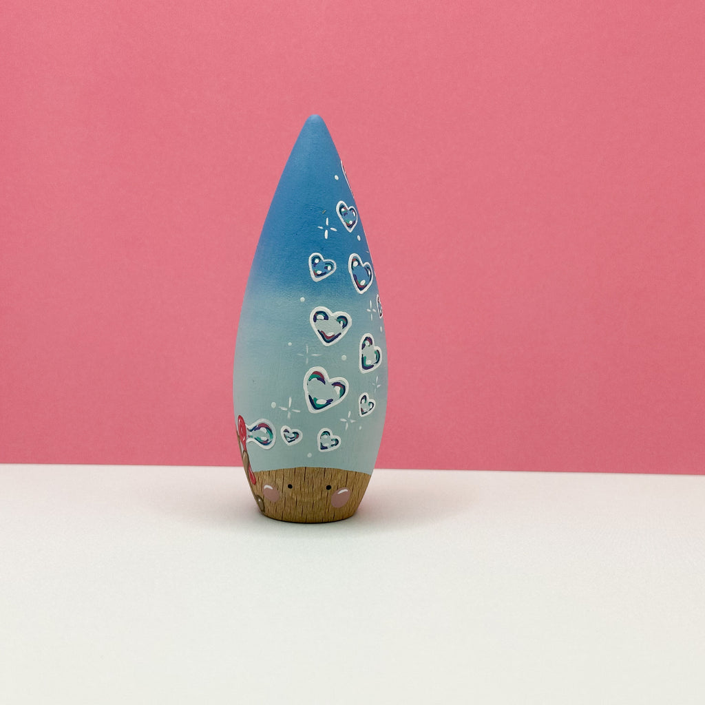 Blue cone shaped toy with heart patterns on a pink background